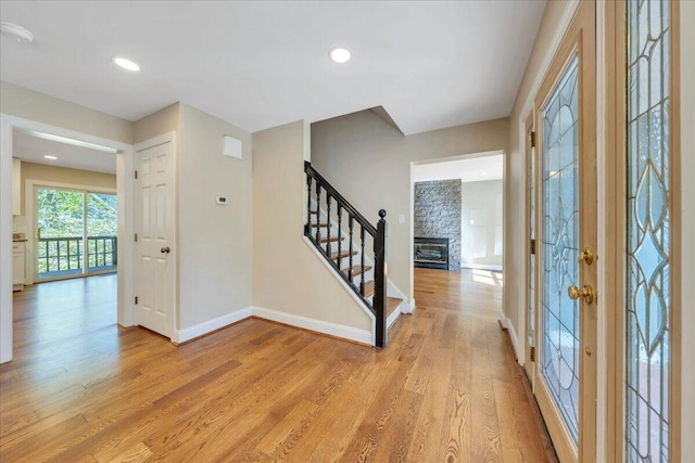 foyer with light wood-style flooring, baseboards, recessed lighting, and stairway