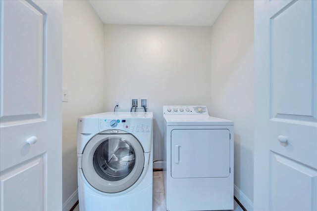 clothes washing area featuring washing machine and clothes dryer, baseboards, and laundry area