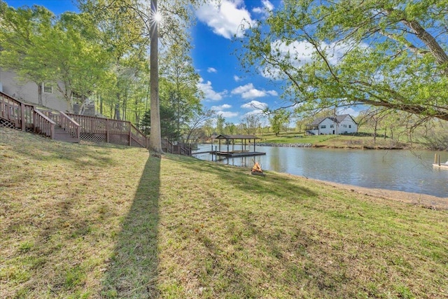 view of dock with a water view and a yard