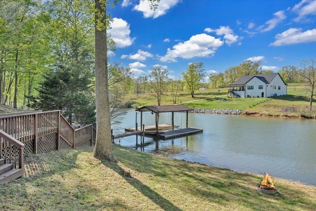 dock area featuring stairway, an outdoor fire pit, a yard, and a water view