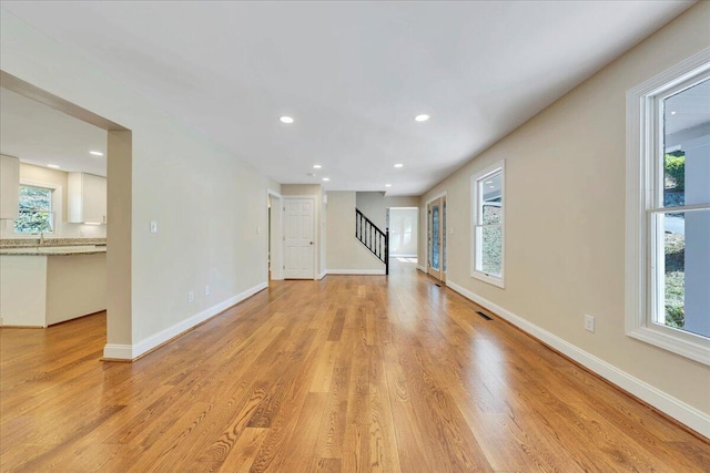 unfurnished living room featuring recessed lighting, stairway, visible vents, baseboards, and light wood-style flooring