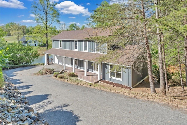 view of front of house featuring roof with shingles, a porch, an attached garage, board and batten siding, and aphalt driveway