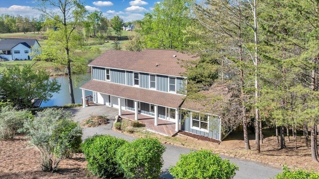back of house featuring aphalt driveway, roof with shingles, covered porch, and a garage