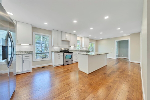 kitchen featuring white cabinets, decorative backsplash, a kitchen island, and appliances with stainless steel finishes