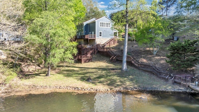 back of property featuring board and batten siding, a deck with water view, and stairs