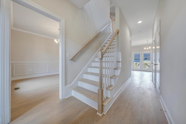 stairway featuring an inviting chandelier, ornamental molding, baseboards, and wood finished floors