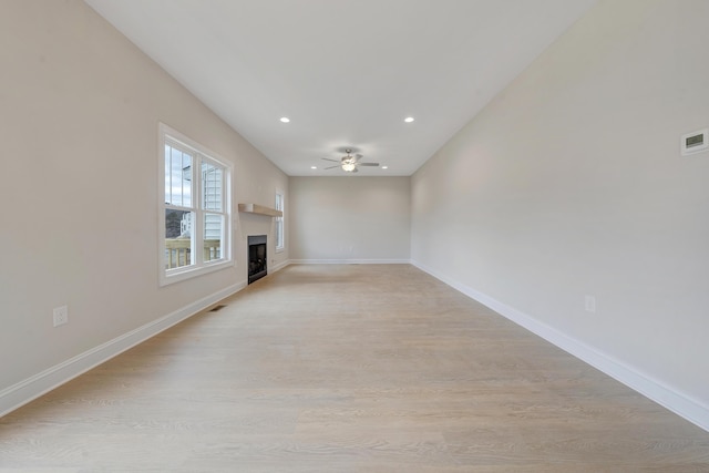 unfurnished living room with a ceiling fan, light wood-style floors, a fireplace, and baseboards