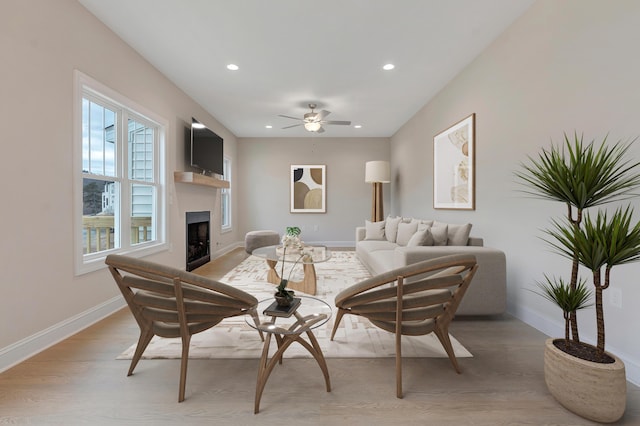 dining room featuring light wood finished floors, a ceiling fan, a fireplace, baseboards, and recessed lighting