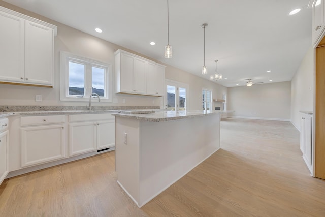 kitchen with a ceiling fan, light wood finished floors, white cabinets, and light stone countertops
