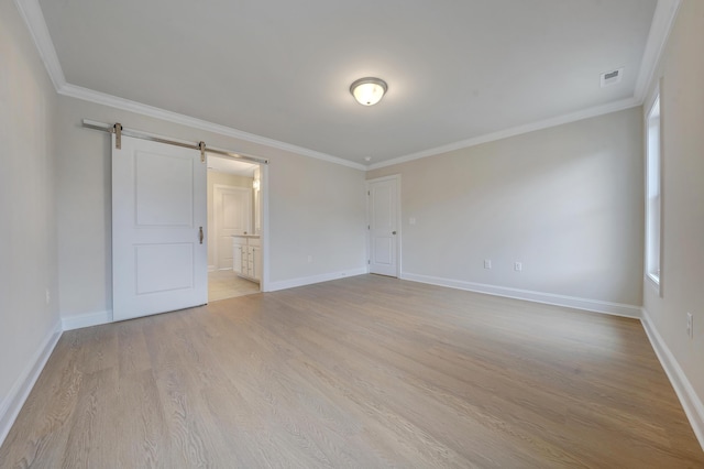 unfurnished room with crown molding, a barn door, and wood finished floors