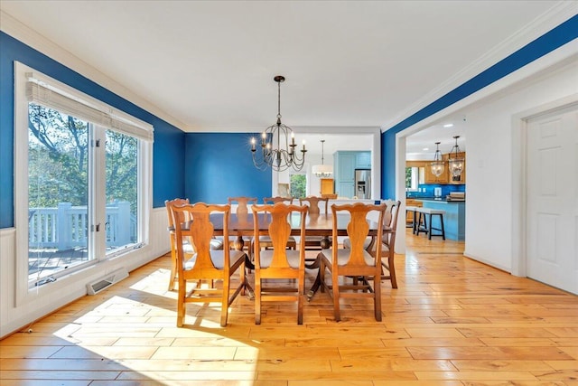dining area featuring an inviting chandelier, light wood-style floors, and a healthy amount of sunlight
