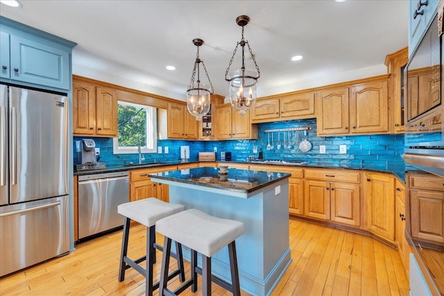 kitchen with stainless steel appliances, a breakfast bar, a sink, and light wood-style flooring