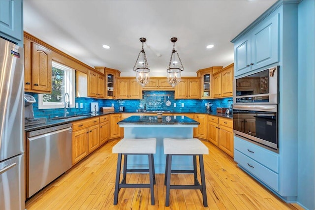 kitchen featuring tasteful backsplash, stainless steel appliances, a kitchen island, and a sink