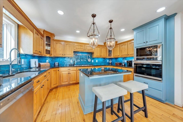 kitchen with an inviting chandelier, glass insert cabinets, stainless steel appliances, and a sink