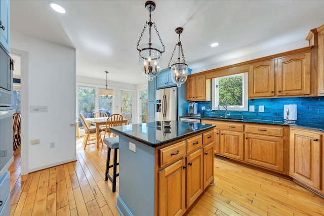 kitchen featuring light wood finished floors, a sink, tasteful backsplash, a chandelier, and stainless steel fridge with ice dispenser