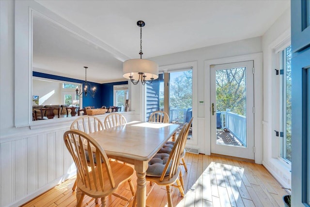 dining space with light wood finished floors, plenty of natural light, and a chandelier