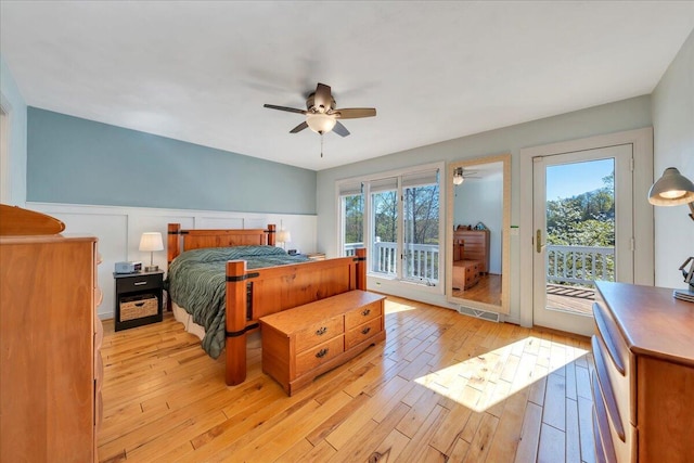bedroom with light wood-style flooring, a wainscoted wall, access to exterior, visible vents, and ceiling fan