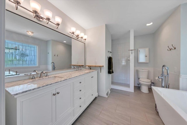 bathroom with a sink, a soaking tub, double vanity, toilet, and tiled shower