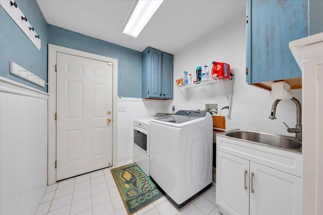 clothes washing area featuring washing machine and dryer, a sink, light tile patterned floors, and cabinet space