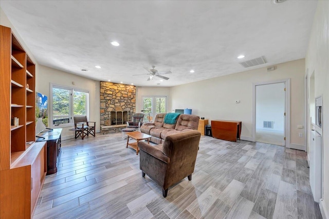 living area featuring visible vents, light wood finished floors, ceiling fan, and a healthy amount of sunlight