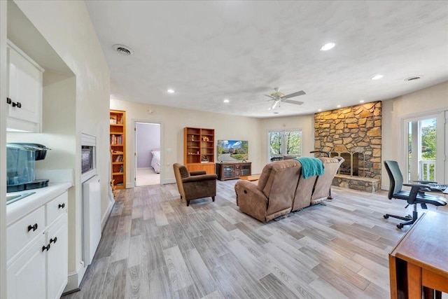 living area featuring light wood-style floors, plenty of natural light, visible vents, and ceiling fan