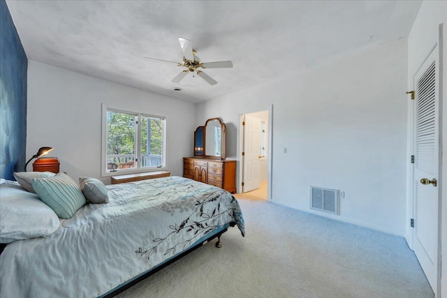 bedroom featuring baseboards, visible vents, light colored carpet, and ceiling fan