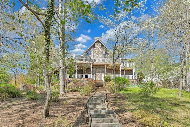 view of front of house featuring stone siding, a balcony, and stairs