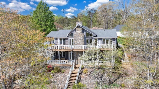 view of front of property featuring stone siding, a shingled roof, a chimney, and a deck