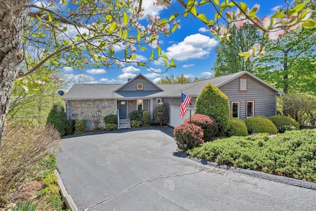 ranch-style home with stone siding, driveway, and a garage