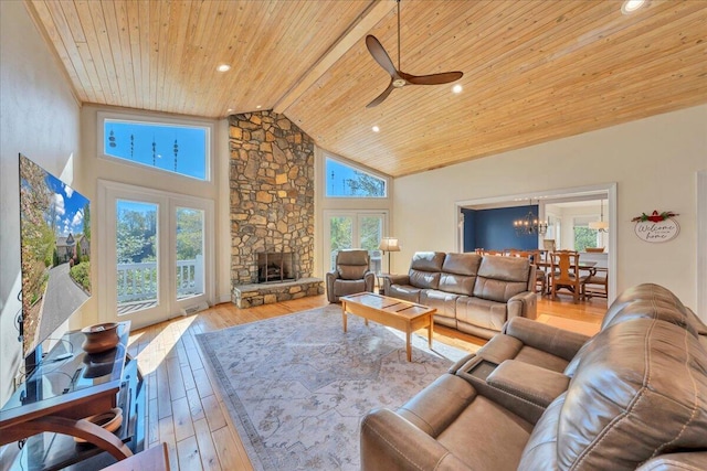 living area with high vaulted ceiling, ceiling fan with notable chandelier, wood finished floors, wood ceiling, and a fireplace