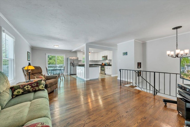 living area with ornamental molding, an inviting chandelier, wood finished floors, and baseboards