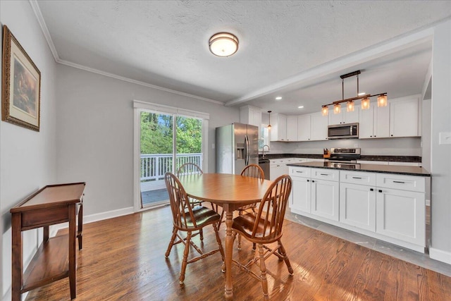 dining space featuring a textured ceiling, wood finished floors, crown molding, and baseboards