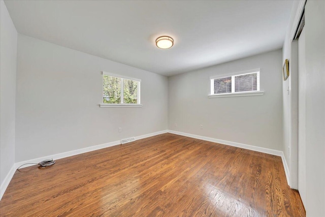 empty room featuring visible vents, wood finished floors, and baseboards