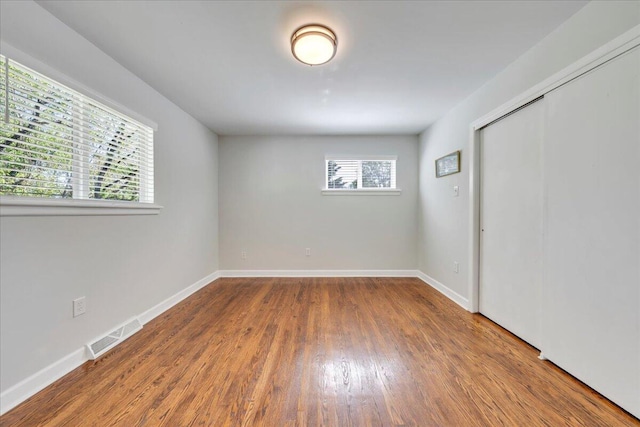 empty room with baseboards, visible vents, and wood finished floors
