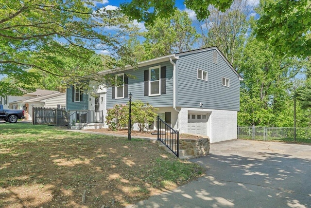 bi-level home with driveway, fence, and a garage