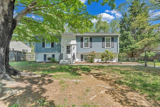 raised ranch with fence and a front lawn