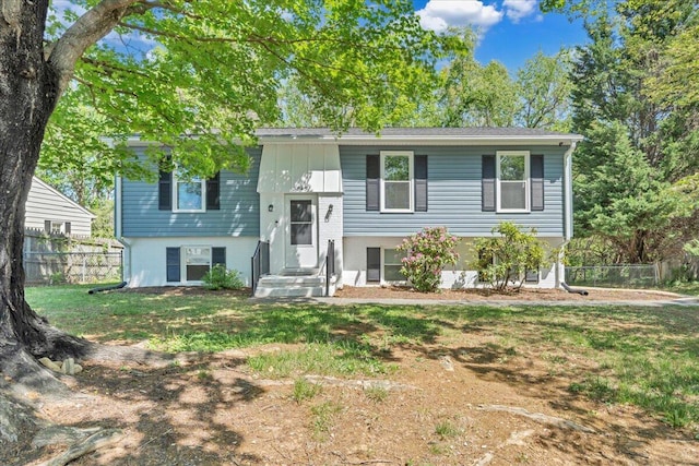 split foyer home featuring fence and a front lawn