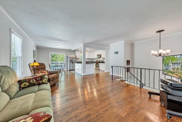 living room with baseboards, wood finished floors, an inviting chandelier, and crown molding