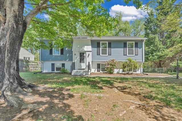 split foyer home featuring a front lawn and fence