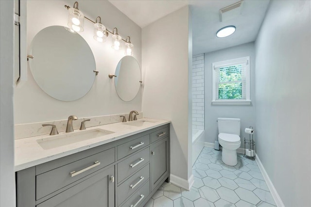 bathroom featuring visible vents, toilet, double vanity, and a sink