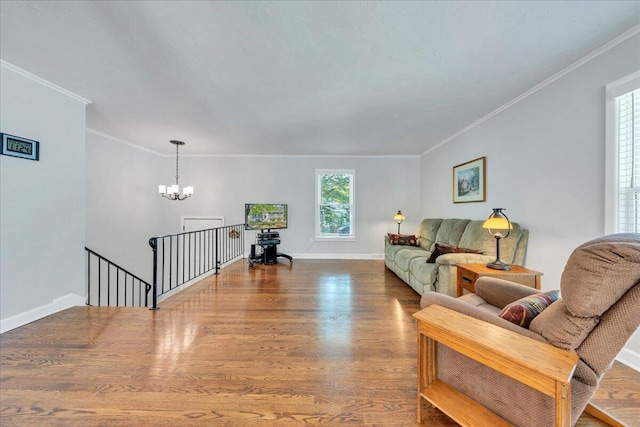living area featuring wood finished floors, crown molding, a chandelier, and baseboards