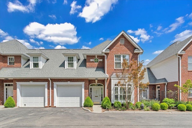 view of front of home with aphalt driveway, a shingled roof, brick siding, and a garage