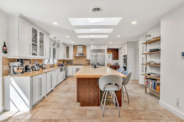 3421 Exeter St SW, Roanoke, VA 24014 - kitchen with stone tile flooring, wall chimney range hood, appliances with stainless steel finishes, and tasteful backsplash