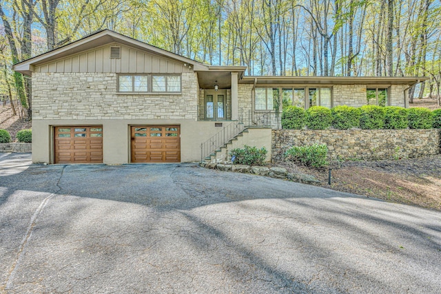 3421 Exeter St SW, Roanoke, VA 24014 - view of front of property with stone siding, an attached garage, stairs, board and batten siding, and aphalt driveway