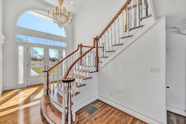 stairway featuring wood finished floors, visible vents, baseboards, and an inviting chandelier