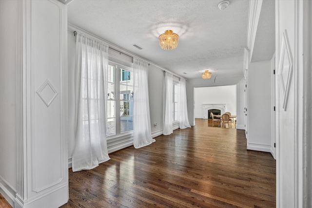 interior space featuring wood finished floors, visible vents, baseboards, a fireplace, and a textured ceiling