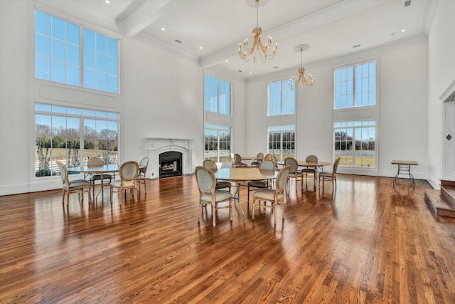 dining space with a high ceiling, a fireplace, a chandelier, and ornamental molding
