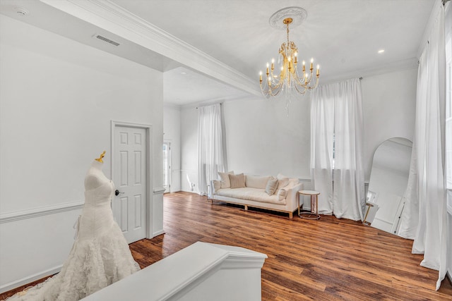 living area featuring wood finished floors, a chandelier, arched walkways, a wealth of natural light, and ornamental molding