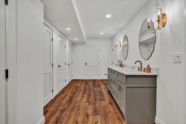 corridor with baseboards, dark wood-style floors, a sink, and recessed lighting