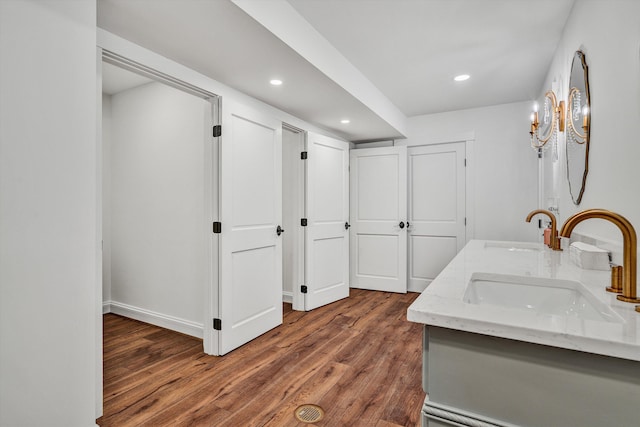 full bath featuring wood finished floors, a sink, double vanity, and recessed lighting
